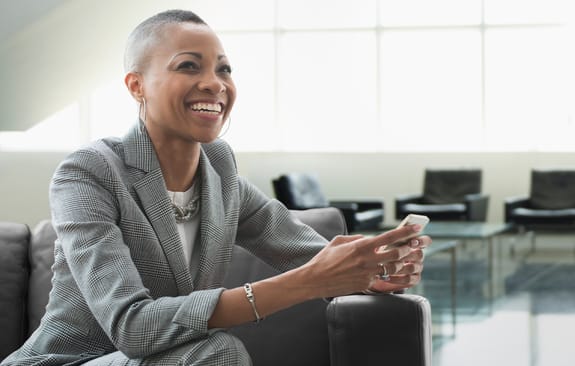 businesswoman using cell phone on sofa in office