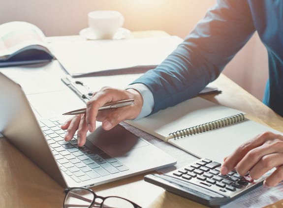 close-up of a male working on laptop and calculator