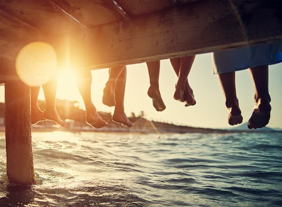 group of peoples feet dangling over water