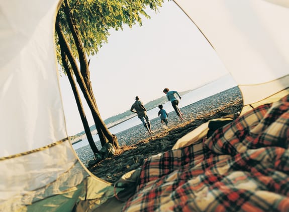 family running on beach away from their tent