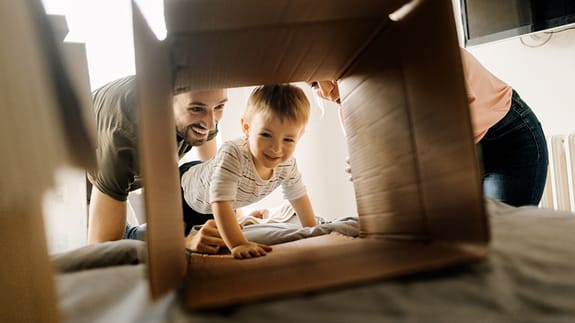 baby crawling through a cardboard box with family