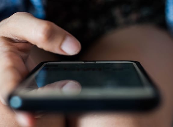 A close up of the hands of a young woman using a mobile phone