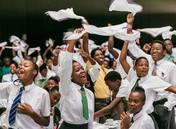 Happy schoolchildren waving white scarves in the air