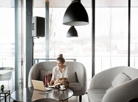 Female sitting on comfy chair in coffee house looking at laptop