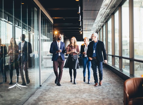 Business people walking along an office corridor as they chat with one another