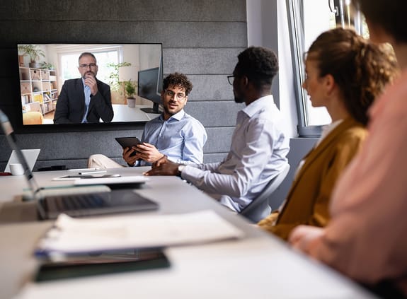 Business people around conference desk engaging in VC meeting