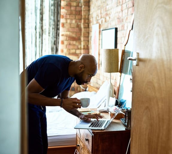 Man drinking a coffee, while on a laptop