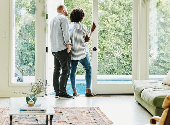 Couple standing looking out a window at home