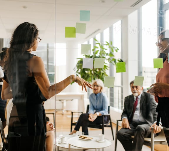 team discussing work in a meeting with notes on a meeting board