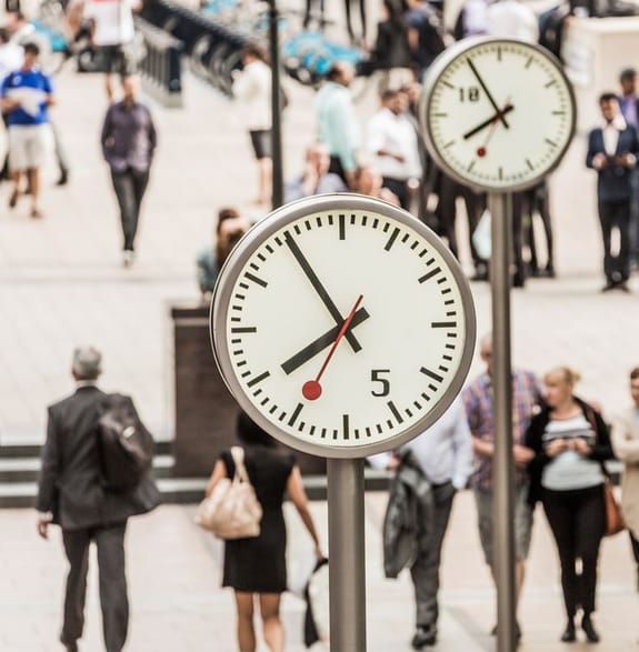 Crowds of office workers walk under the clocks of Canary Wharf