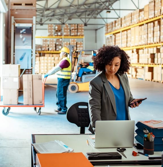 Warehouse manager checks computer while boxes are loaded