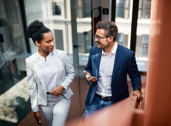 Business colleagues walking up staircase chatting in modern office