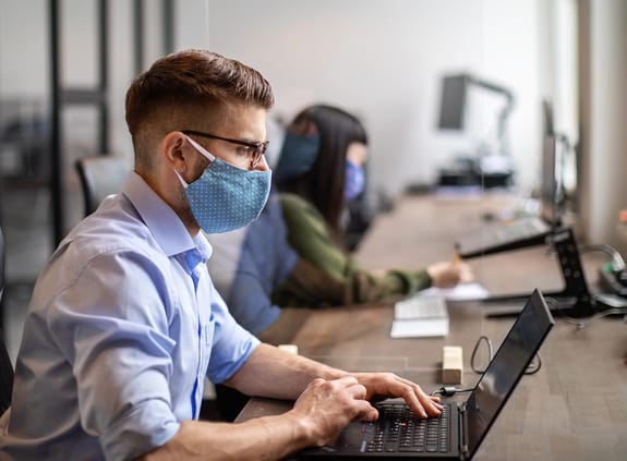 Man working at desk with a mask on