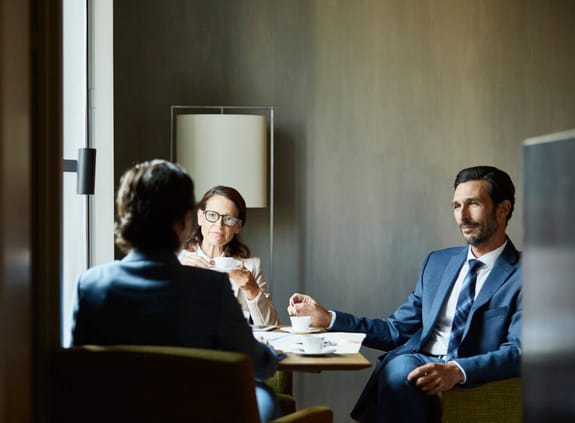 Two financial advisers talk with a client in a meeting