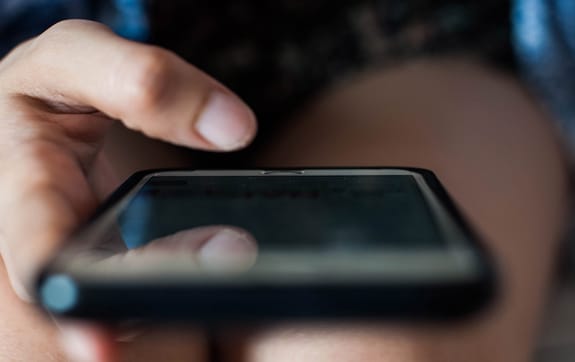 A person's thumb hovers over a smartphone screen