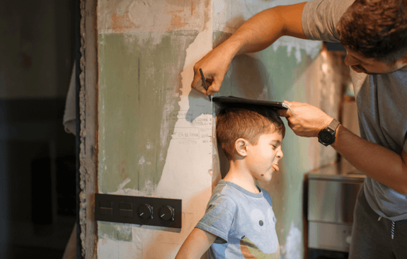 man measuring boys height against a wall
