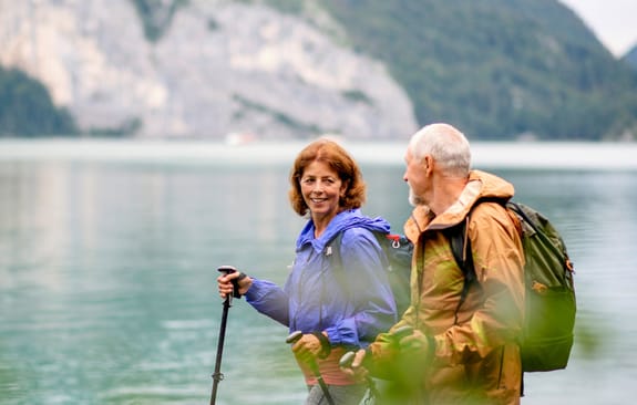 Happy middle-aged couple hiking by the water