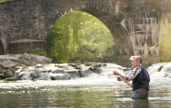 Middle-aged man fly fishing in a river