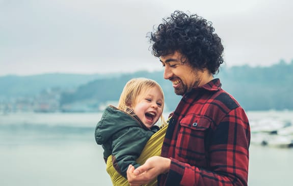Man smiling down on child he's carrying