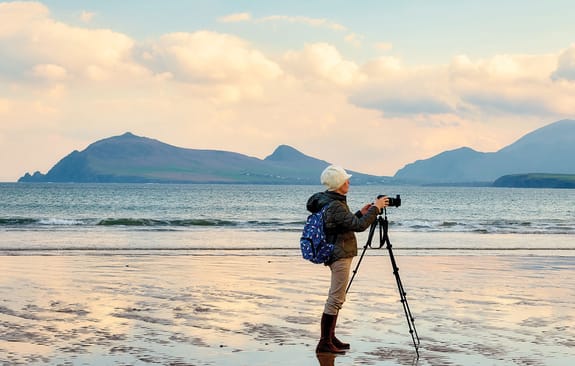 Photographer with a tripod capturing a still beach at sunset