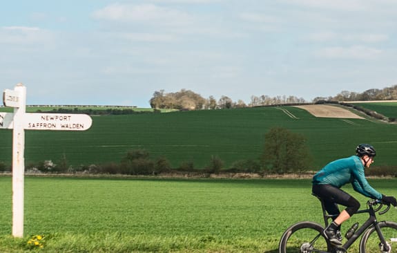 Cyclist passing roadsign in the English countryside