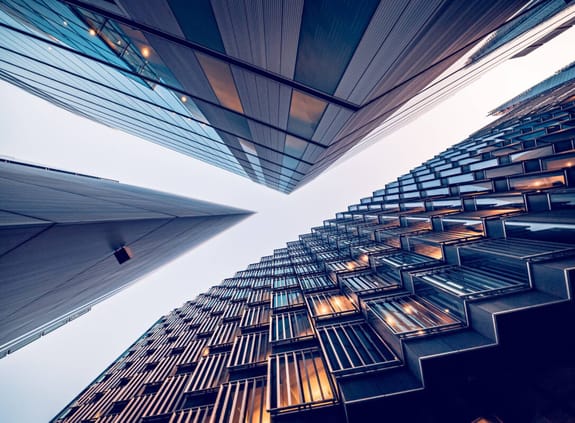 Looking up to the sky through glass-edged skyscrappers in the city