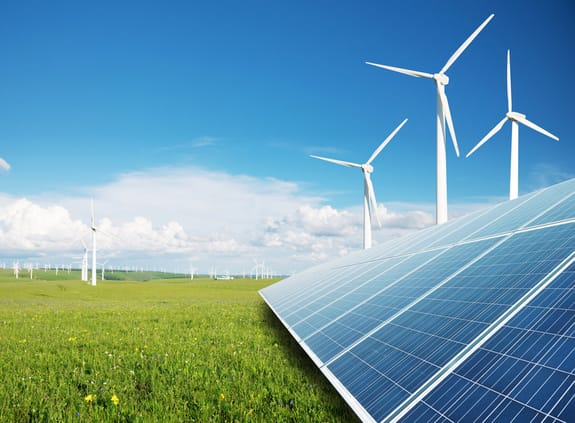 Solar panels alongside wind turbines in a green field