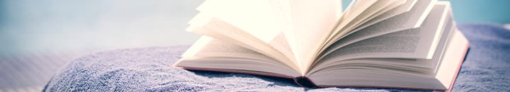 Book sitting on top of a towel by swimming pool