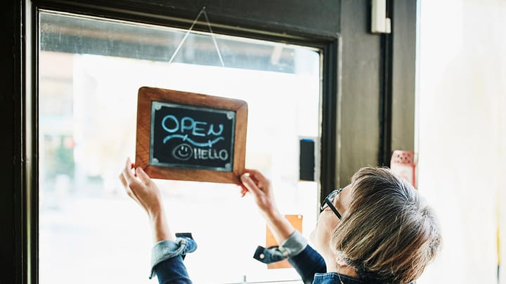 Women turning an open-for-business sign