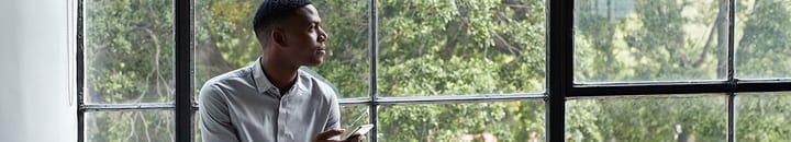 Man with phone staring out of window