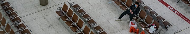 Lone man wearing face mask, sitting in empty airport terminal