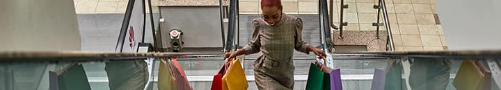 Female shopper going up an escalator with shopping bags