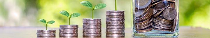 Stacks of coins and a jar of coins showing growth