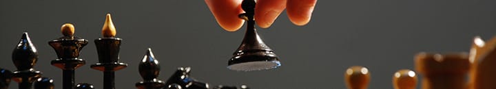 Black pawn in a chess set being lifted into place