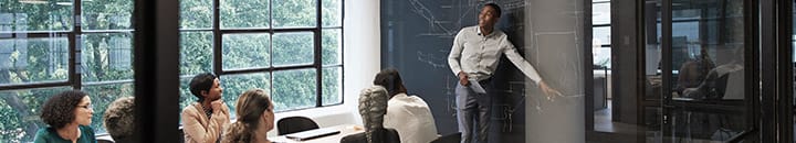 Team discussing in a meeting room with a male at the white board