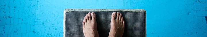 Feet on edge of diving board ready to jump into the pool