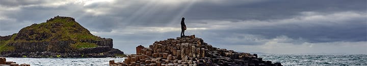 Person standing on top of a pile of rocks in the sea