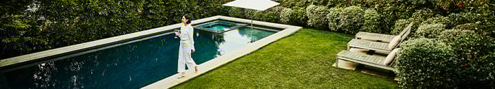 female walking around her back garden with outdoor swimming pool