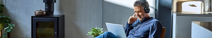 Male sitting in lounge with laptop and earphones