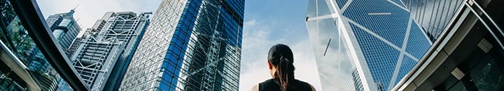 Business woman looking up at office buildings