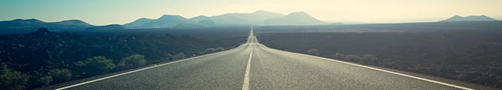 empty highway with mountains in the background