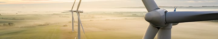 Wind turbines against a sun rise with fog
