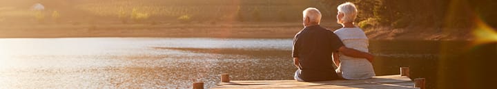 Older couple sitting on a dock looking out over a lake