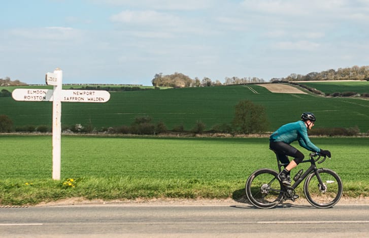 Cyclist passing roadsign in English countryside