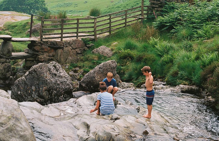Three young children playing in a local riverbed