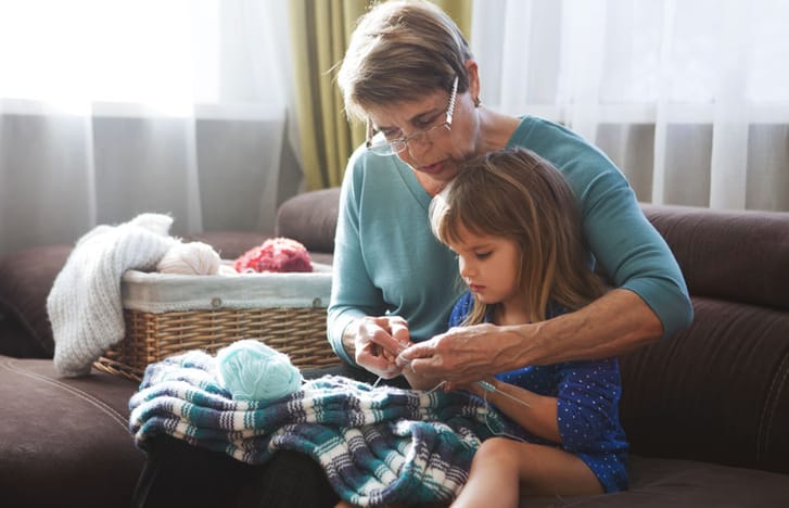 Woman teaching her granddaughter to knit