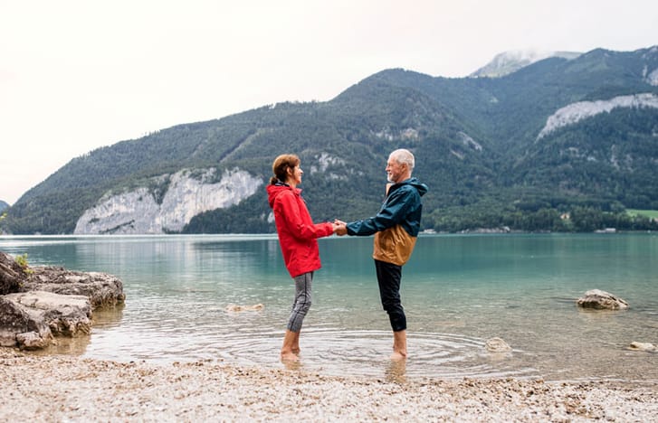 A couple standing in the shallows of a lake holding hands