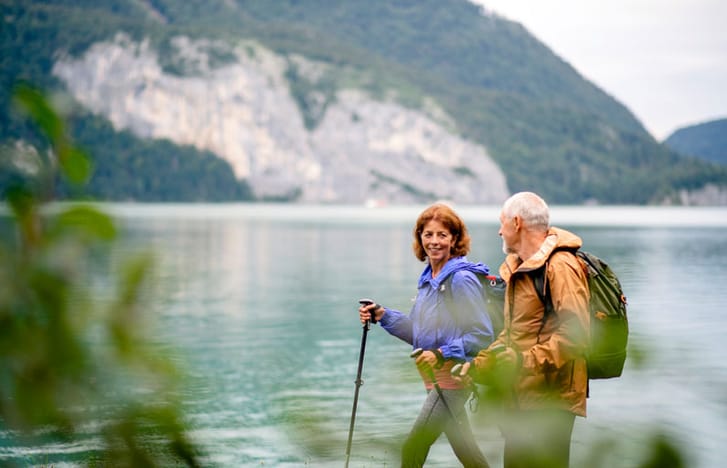 Happy middle-aged couple hiking by the water