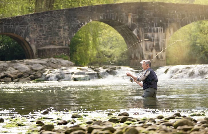 Middle-aged man fly fishing in a river