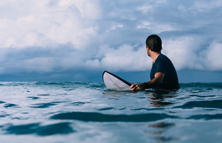 Surfer in the ocean looks back at next wave